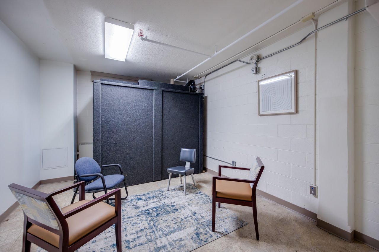 A music practice room, complete with a grey soundproof booth and multiple chairs for students to use.