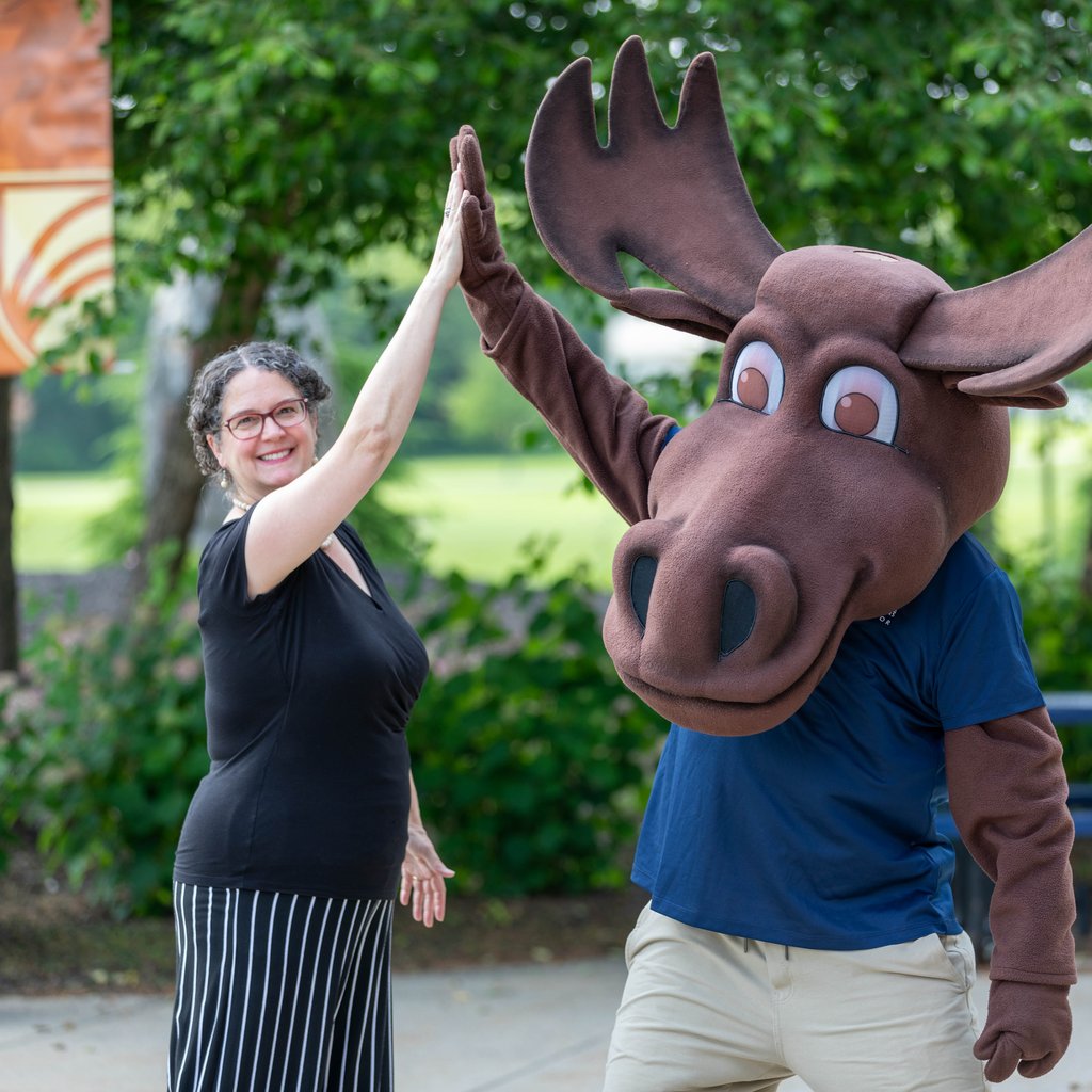UMA President Dr. Cushman high-fiving UMA mascot Augustus Moose